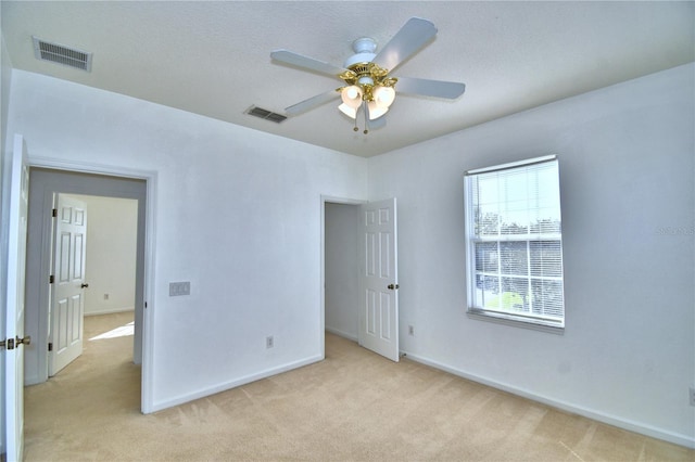 unfurnished bedroom featuring visible vents, ceiling fan, light carpet, and baseboards