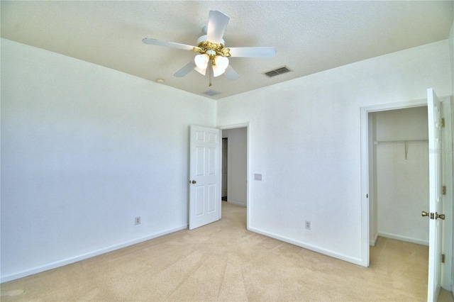 unfurnished bedroom with light carpet, baseboards, visible vents, a walk in closet, and a closet