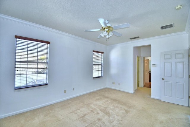 spare room featuring crown molding, visible vents, light carpet, a textured ceiling, and baseboards