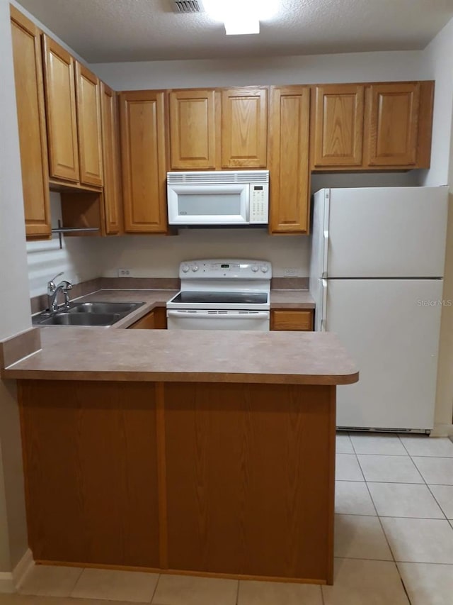 kitchen featuring light countertops, white appliances, light tile patterned flooring, and a sink