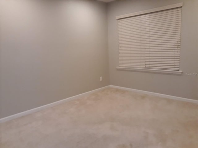 carpeted spare room featuring baseboards