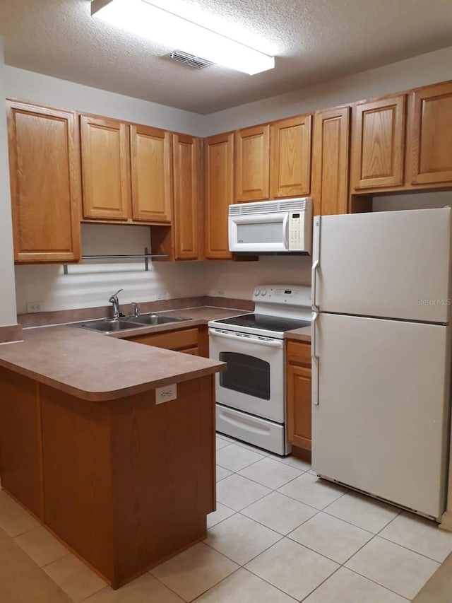 kitchen featuring a peninsula, white appliances, a sink, visible vents, and light countertops