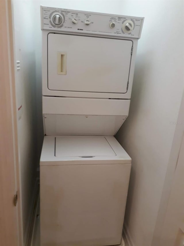 clothes washing area featuring stacked washer and dryer and laundry area