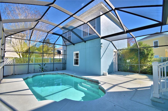 view of swimming pool featuring glass enclosure, a patio area, fence, and a fenced in pool