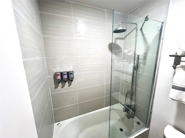 bathroom featuring toilet and combined bath / shower with glass door