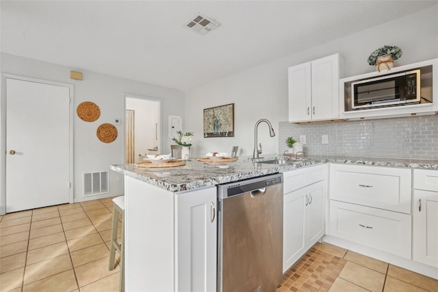 kitchen featuring a sink, visible vents, dishwasher, and a peninsula