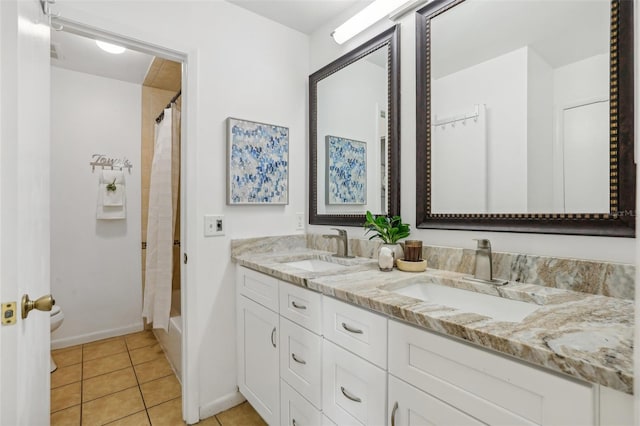 full bathroom with tile patterned floors, double vanity, baseboards, and a sink