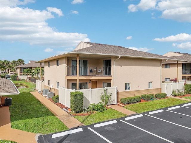 view of property with cooling unit, uncovered parking, and fence