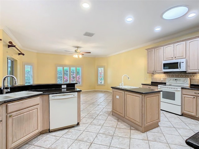 kitchen with dark countertops, white appliances, a sink, and light brown cabinetry