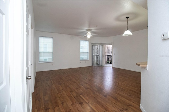 spare room with dark wood-type flooring, ceiling fan, and baseboards