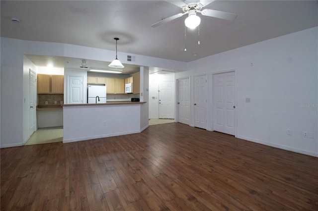 unfurnished living room with dark wood-style floors, baseboards, visible vents, and a ceiling fan