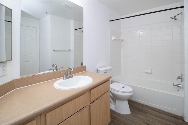 bathroom featuring toilet, wood finished floors, vanity, visible vents, and washtub / shower combination