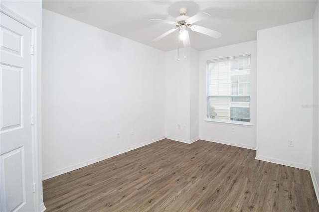 unfurnished room with ceiling fan, dark wood finished floors, and baseboards