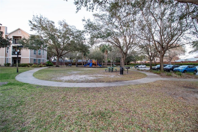 view of property's community featuring playground community and a yard