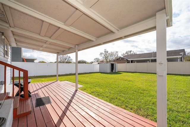 deck featuring a storage unit, a lawn, and a fenced backyard