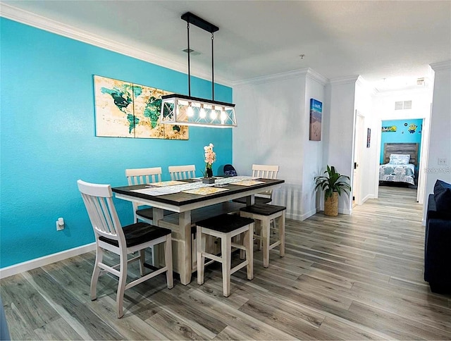 dining space featuring baseboards, wood finished floors, and crown molding