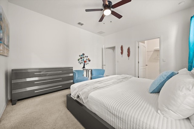 bedroom featuring light carpet, a walk in closet, and ceiling fan