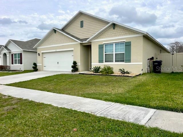 view of front of home with concrete driveway, a front lawn, an attached garage, and stucco siding