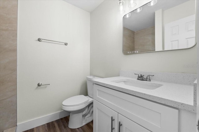 bathroom with baseboards, toilet, wood finished floors, and vanity