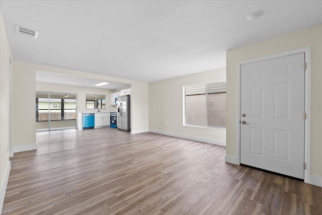 unfurnished living room with visible vents, baseboards, and light wood-style floors