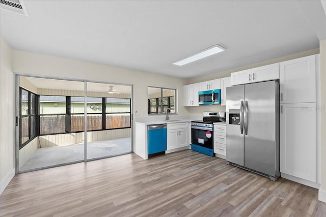 kitchen with visible vents, light countertops, light wood-type flooring, white cabinets, and stainless steel appliances