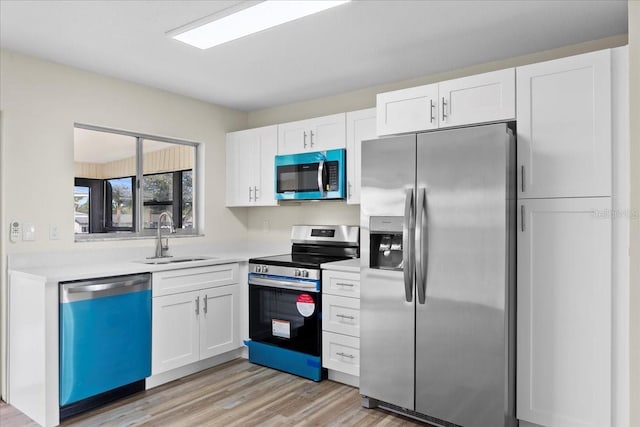 kitchen with a sink, appliances with stainless steel finishes, white cabinets, and light countertops