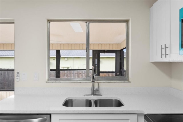 kitchen with dishwasher, white cabinetry, and a sink