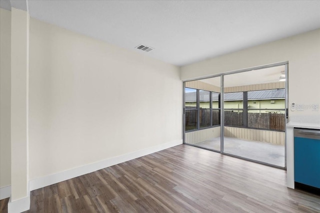 empty room featuring wood finished floors, visible vents, and baseboards