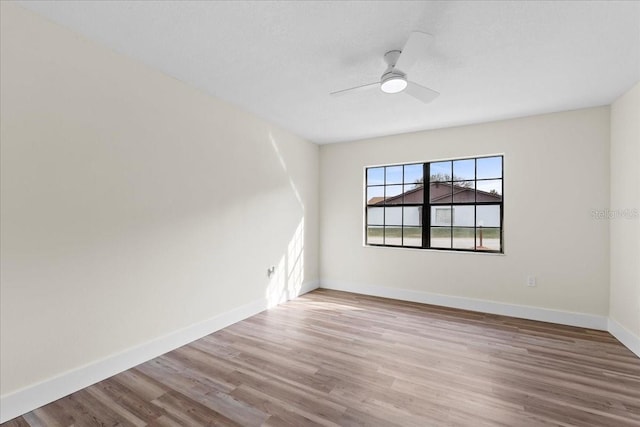 empty room with baseboards, wood finished floors, and a ceiling fan