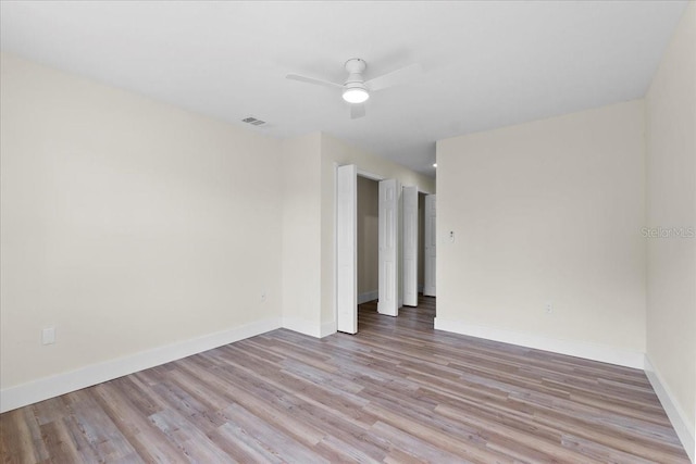 empty room featuring visible vents, ceiling fan, baseboards, and wood finished floors