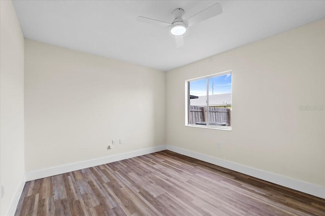 spare room featuring ceiling fan, baseboards, and wood finished floors