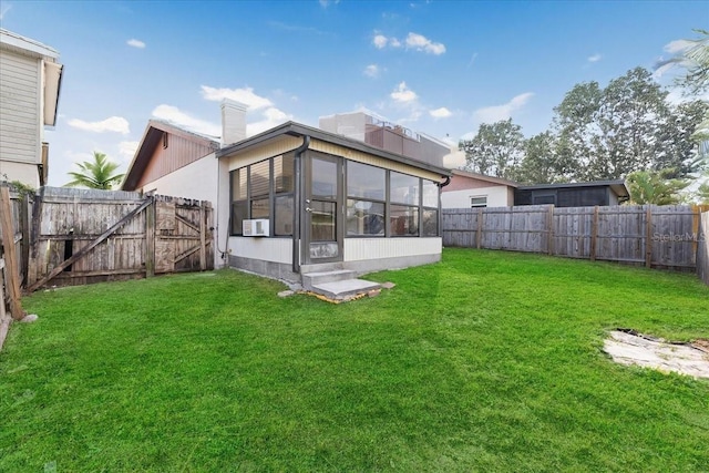 back of house featuring a lawn, a chimney, a fenced backyard, and a sunroom