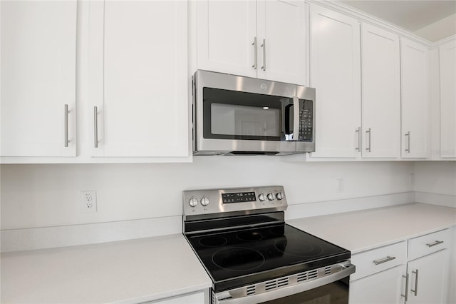 kitchen featuring stainless steel appliances, light countertops, and white cabinets