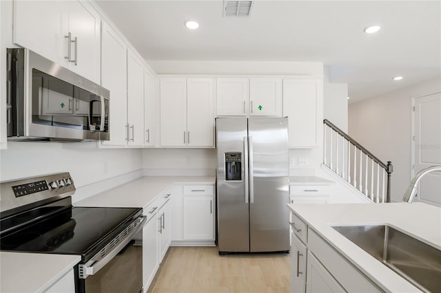 kitchen with stainless steel appliances, light countertops, a sink, and visible vents