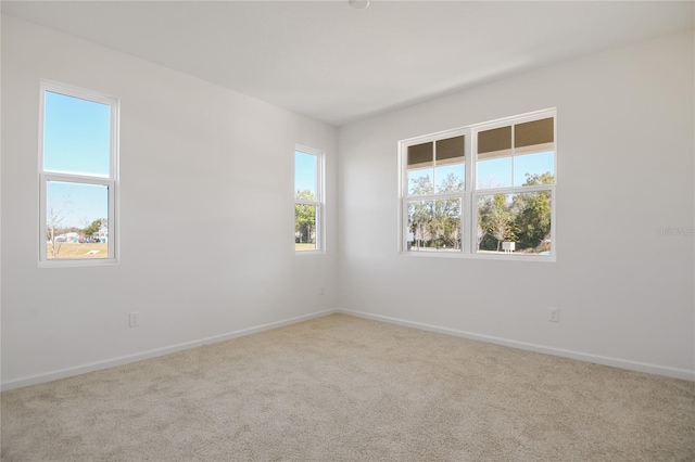 empty room featuring light colored carpet and baseboards