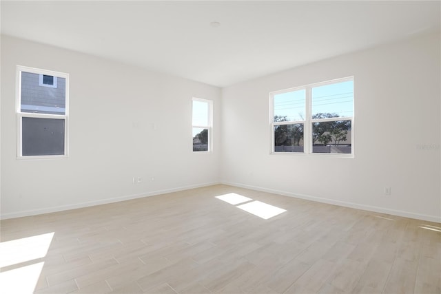 unfurnished room with light wood-type flooring and baseboards