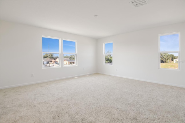 empty room featuring light carpet, baseboards, and visible vents