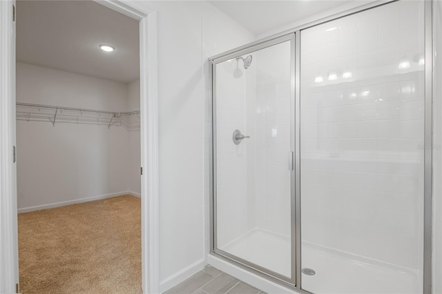 bathroom featuring a stall shower, a spacious closet, and baseboards