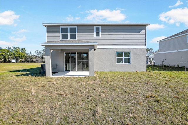 rear view of property featuring a patio area, a lawn, and stucco siding