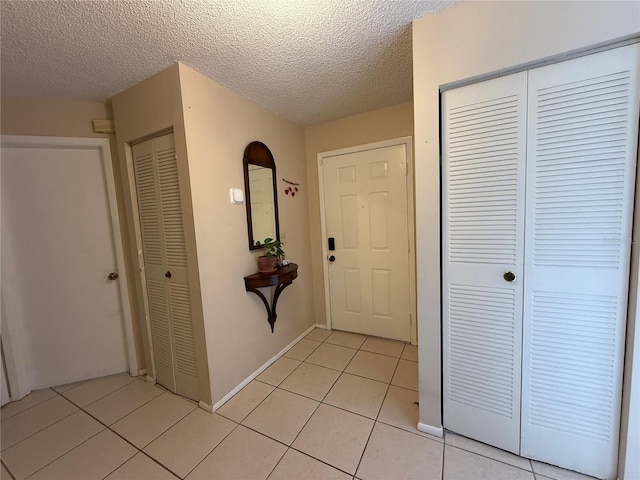 interior space featuring light tile patterned floors, baseboards, and a textured ceiling