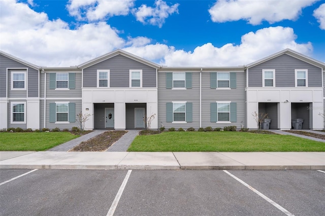 view of property featuring uncovered parking and a front lawn