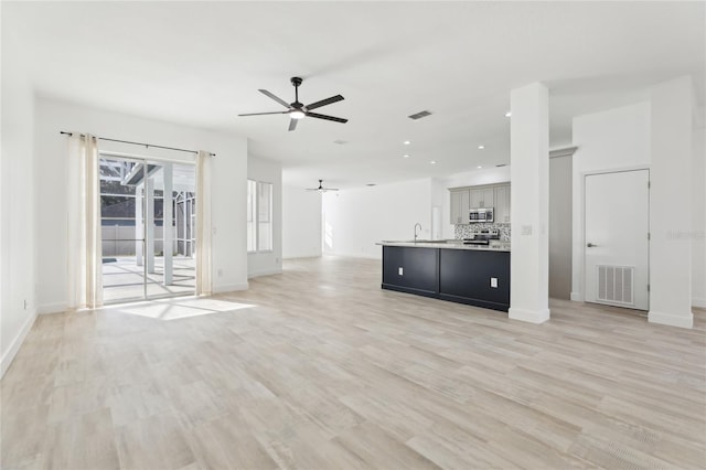 unfurnished living room with light hardwood / wood-style flooring, ceiling fan, and sink