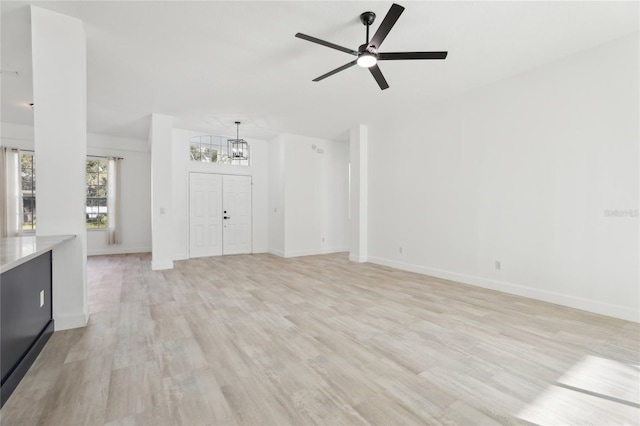 unfurnished living room featuring light hardwood / wood-style floors and ceiling fan with notable chandelier