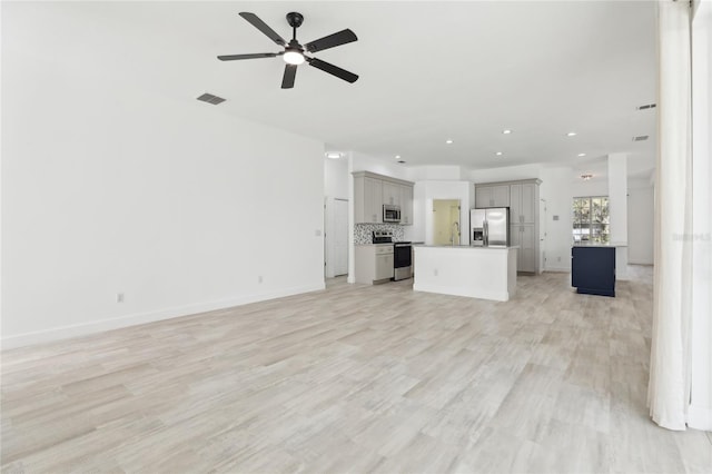 unfurnished living room featuring sink, ceiling fan, and light hardwood / wood-style floors