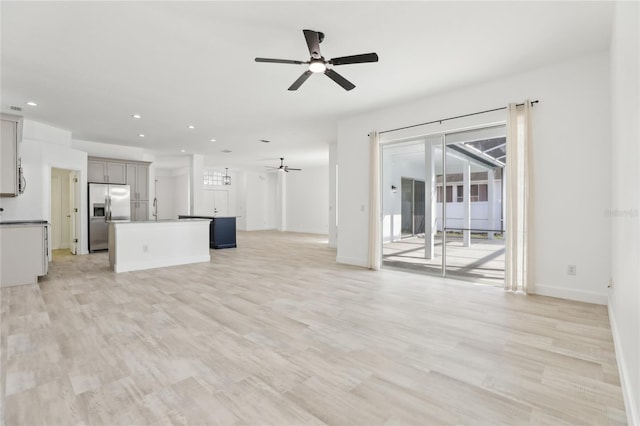 unfurnished living room with sink, ceiling fan, and light hardwood / wood-style flooring