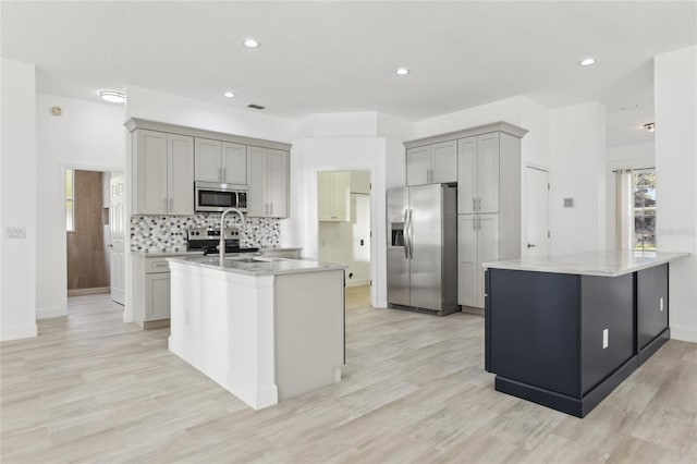kitchen featuring gray cabinets, sink, stainless steel appliances, and light stone countertops