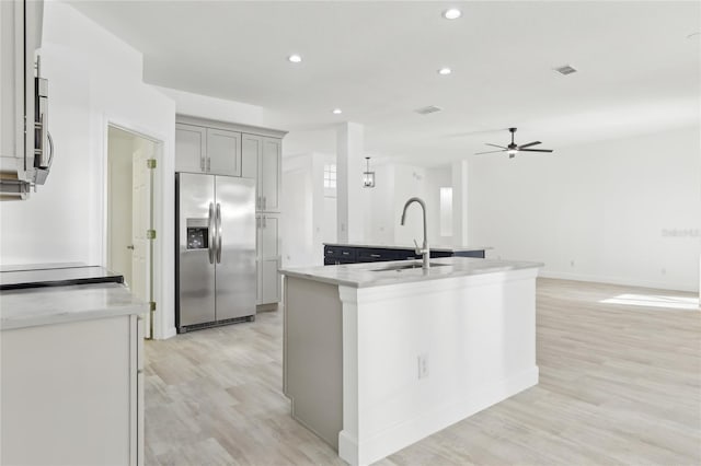 kitchen featuring stainless steel appliances, light hardwood / wood-style floors, gray cabinets, sink, and a kitchen island with sink