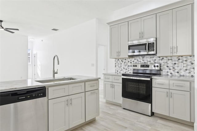kitchen with light hardwood / wood-style flooring, sink, backsplash, ceiling fan, and stainless steel appliances