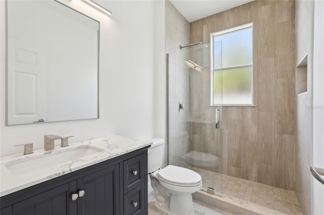 bathroom with toilet, vanity, and a shower with shower door