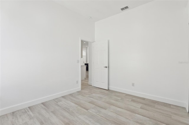 empty room featuring light wood-type flooring and a high ceiling
